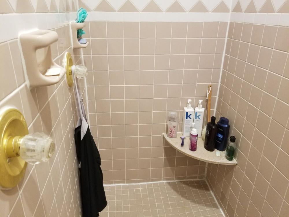 Before tight cramped and outdated shower with tiles that are not level and grout staining. Brass and glass shower valves and plastic benches and soap dishes topped off the beige beauty.