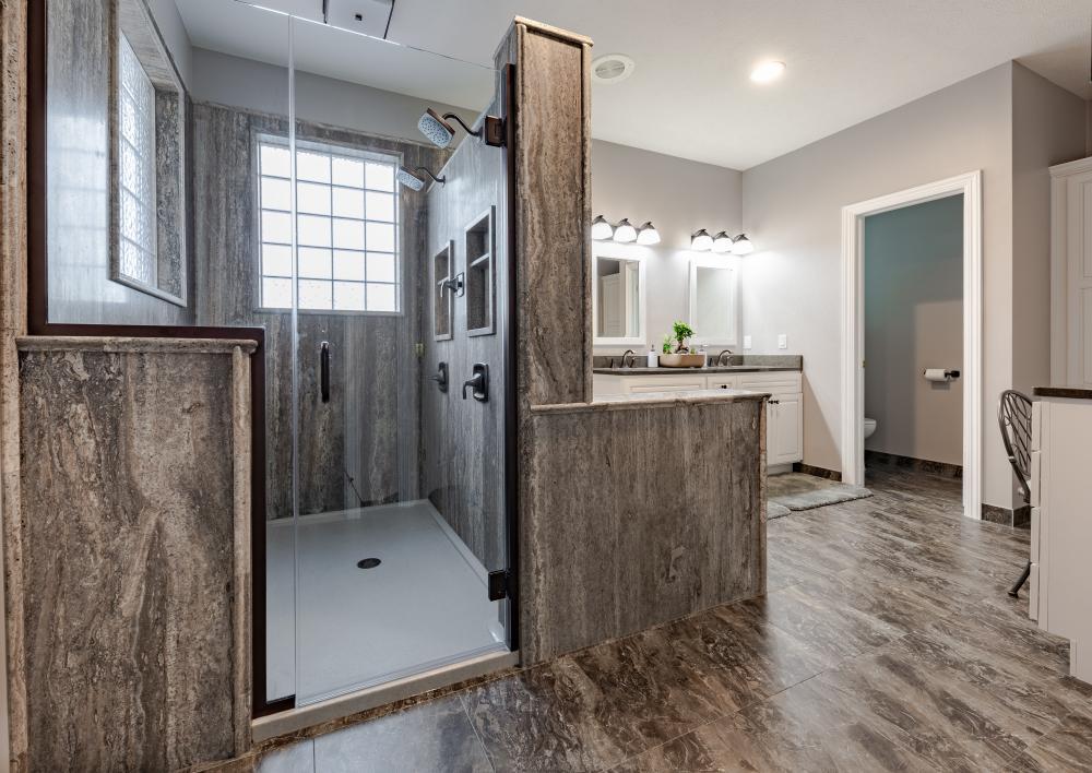 If you are considering a bathroom remodel Omaha, consider the expertise of ReBath. This double stone shower in travertine slab stone with custom bathroom flooring by DuraCeramic and custom bathroom vanity, make-up table and linen closet by Bertch makes this transitional bathroom design a luxury bathroom makeover dream.