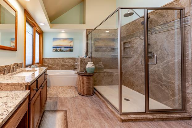 This complete bathroom remodel in Omaha features the beauty of traditional bathroom design with a beach theme. This marble stone slab shower update and glass surround is the highlight of this bathroom makeover. The bathroom renovation also included a tub replacement, custom oak vanity with quartz counter tops, and Duraceramic tile floor as well.