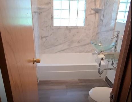 The smooth DuraBath Calcutta can be used in contemporary, modern or traditional design. It works well with this self-installed modern sink and gray-toned luxury vinyl plank.