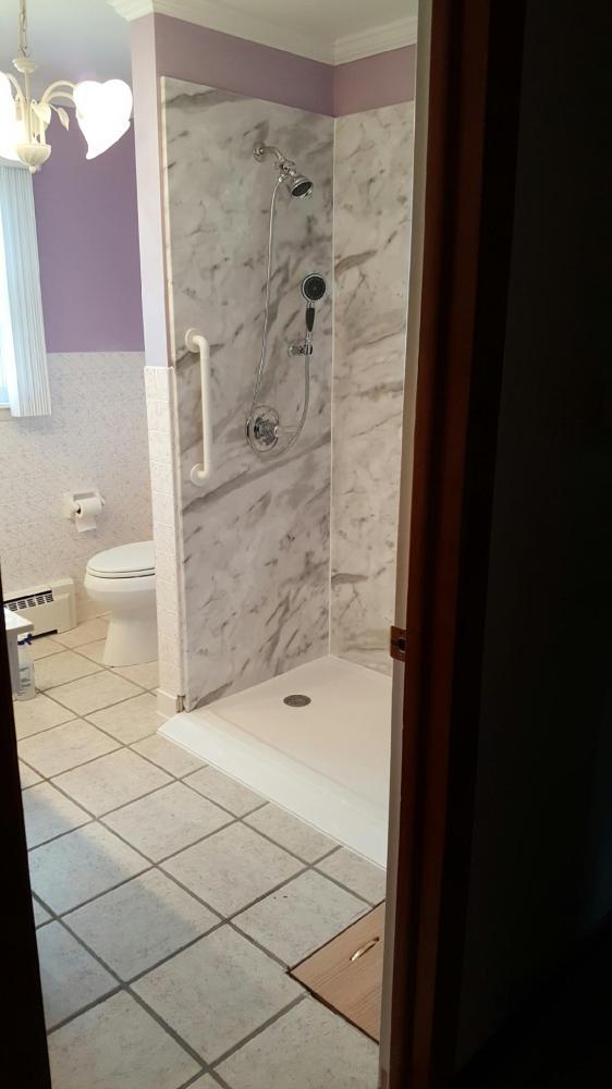 White Calcutta walls with a roll-in shower for wheelchair accessibility.