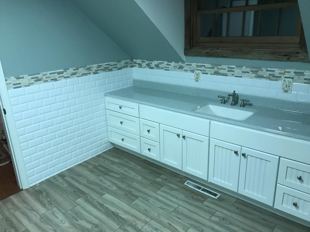 White classic subway wainscot with the decorative mosaic tiles, white centennial style vanity, lotus onyx vanity top with clean white bowl, and the beautiful and popular naturale floating porcelain tile planks!