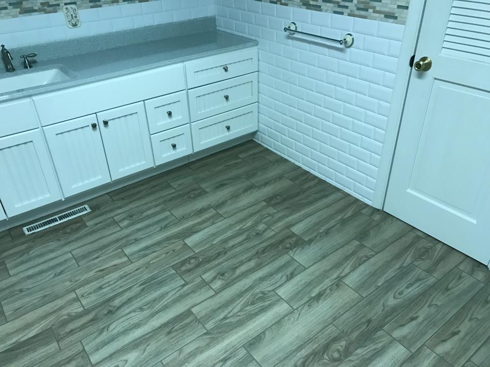 White classic subway wainscot with the decorative mosaic tiles, white centennial style vanity, lotus onyx vanity top with clean white bowl, and the beautiful and popular naturale floating porcelain tile planks!