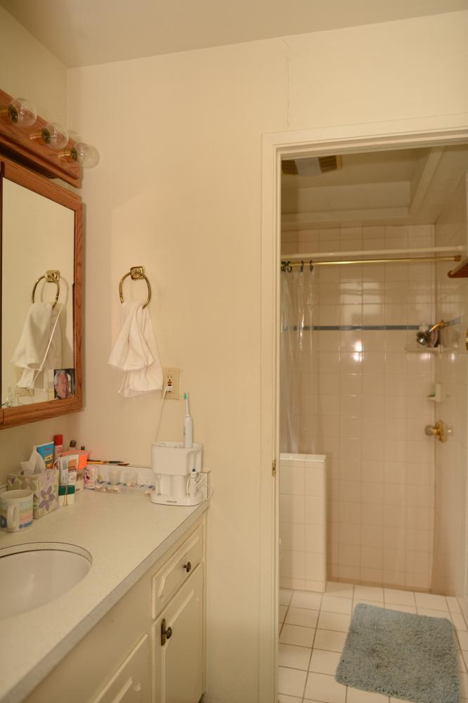 This tired bathroom was stuck in the 70's. The shower and floor had tile with grout that was almost impossible to keep clean. The vanity doors didn't operate well and the shower curtain wasn't effective in keeping water inside the shower.