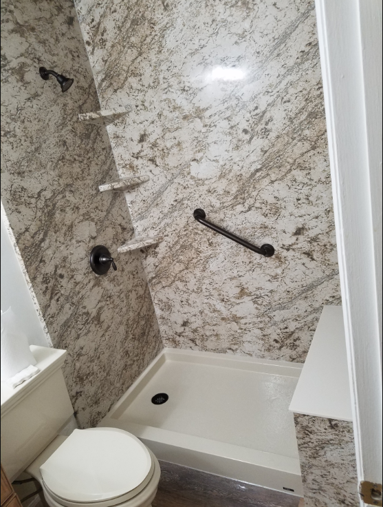 Custom Shower featuring low threshold shower pan, seating, and grab bars