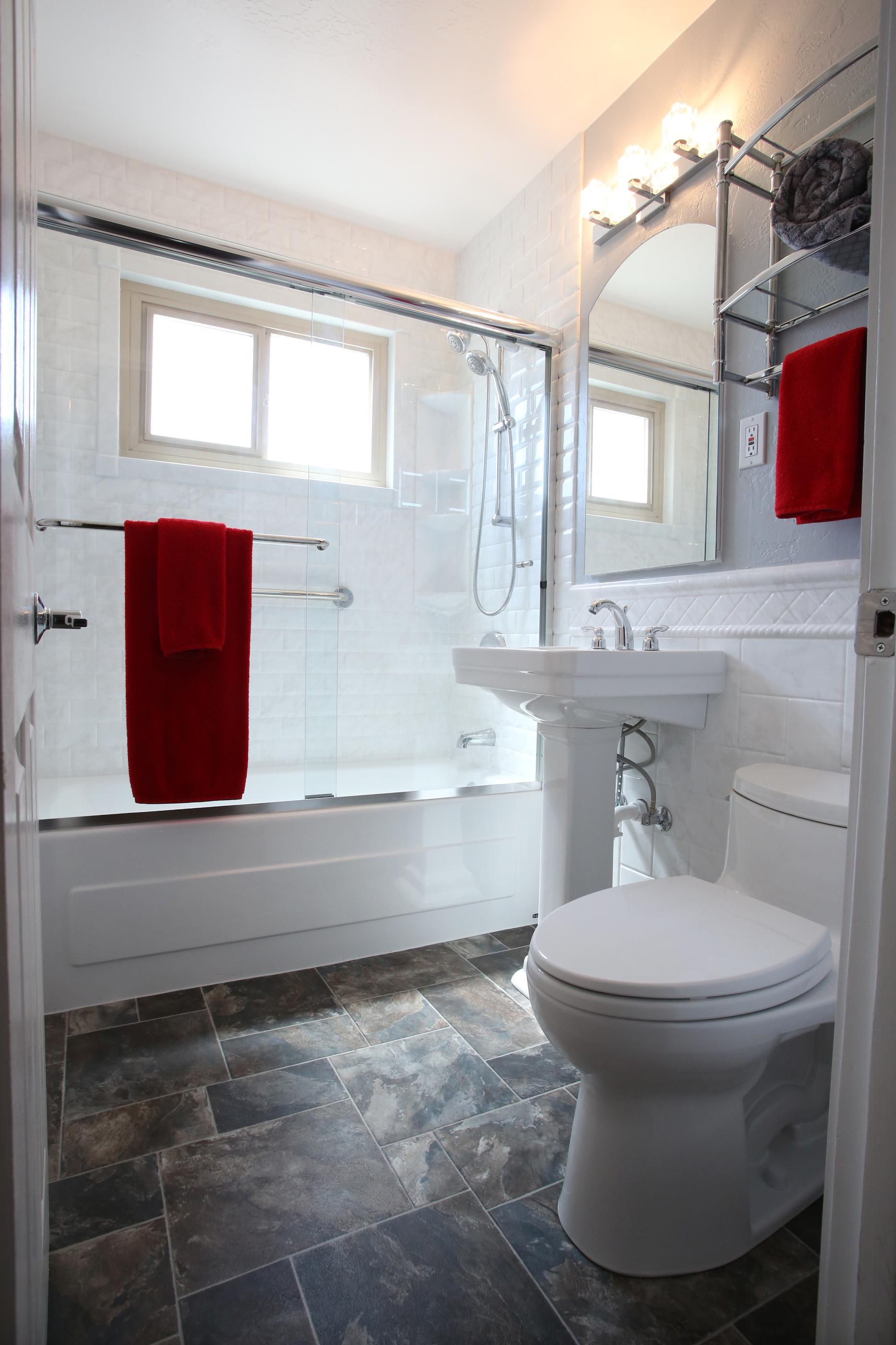 The remodeled bathroom features all new materials. From the flooring to the ceiling the bathroom was redone. The bright white fixtures, new wainscoting and shower door brighten and update what had been a very dark bathroom. ReBath's Durabath product used on the shower walls will make cleaning a breeze!