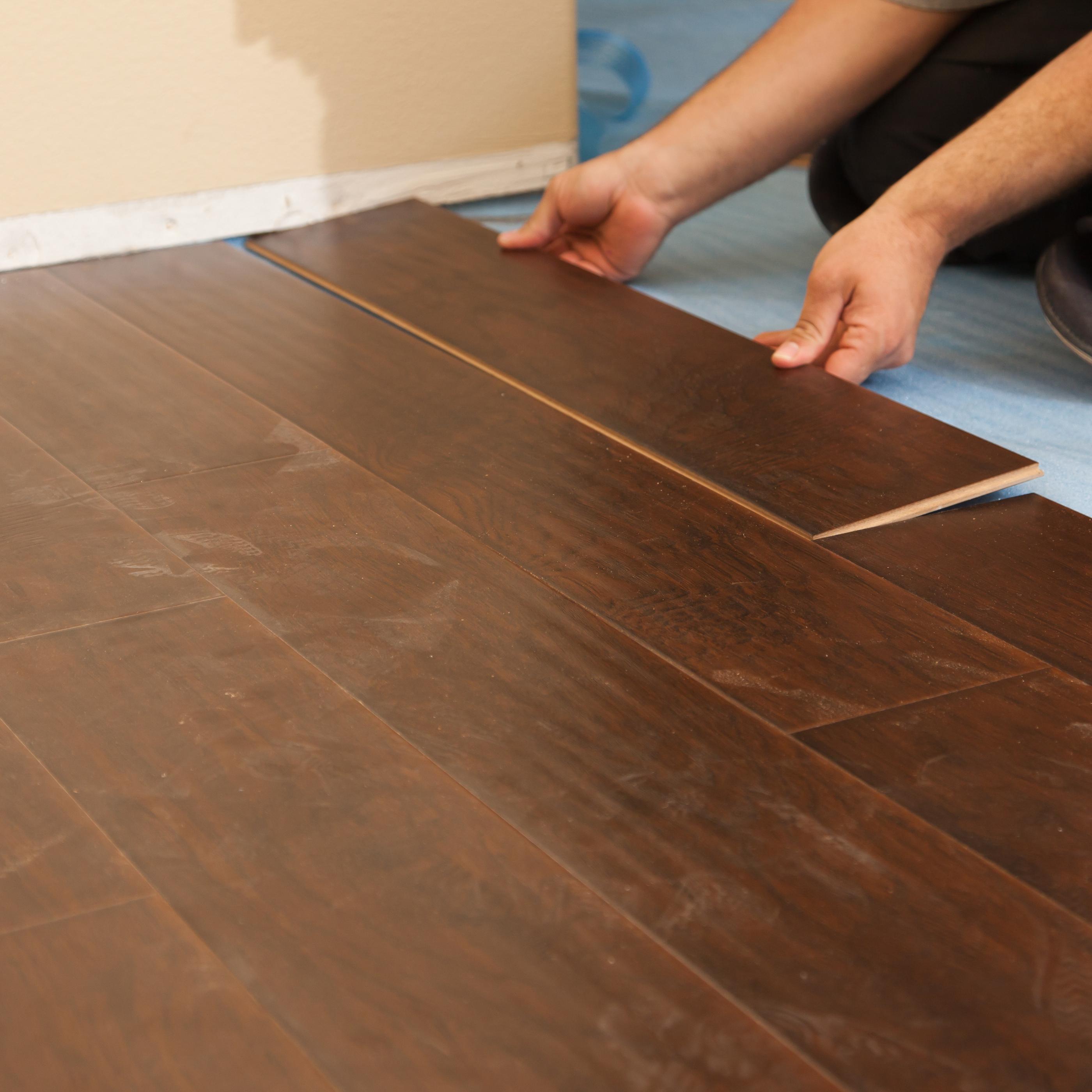Floating laminate floor panels being clicked together without glue or nails.