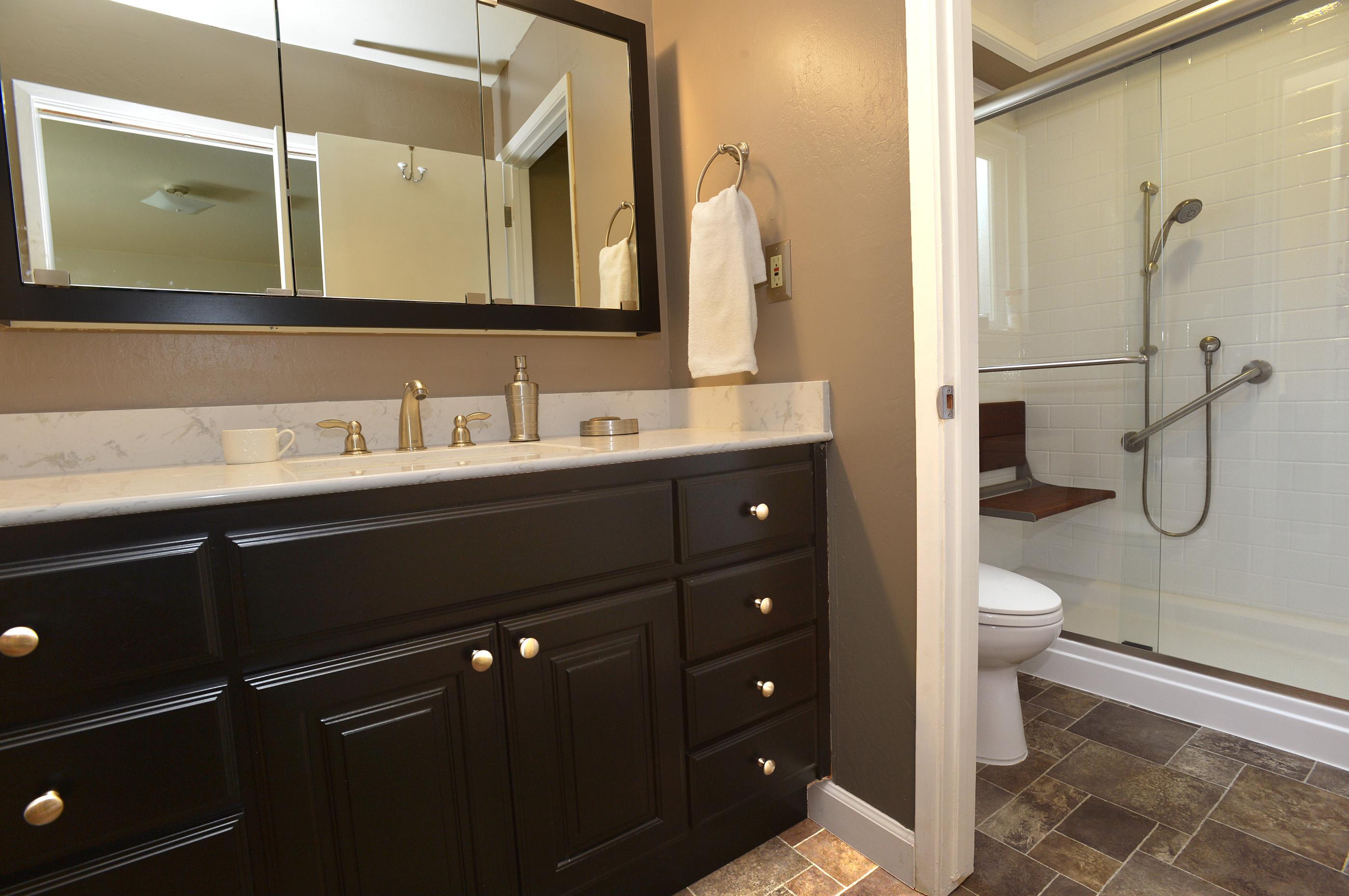 The remodeled ReBath bathroom included a new, higher vanity and counter top, and new lighting and mirror. The flooring and fixtures were also updated with beautiful new materials. The updated shower included a fold down seat, grab bars and a hand held shower head, and a new shower door operates much better than the previous shower curtain. The new Durabath shower walls mean easier maintenance with no grout lines!
