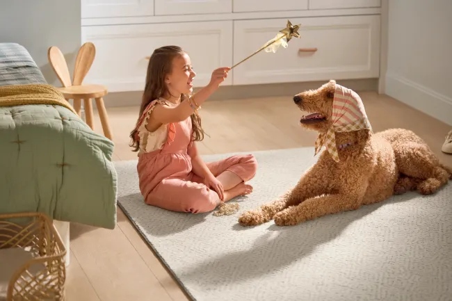 A girl and her dog sitting on a carpet